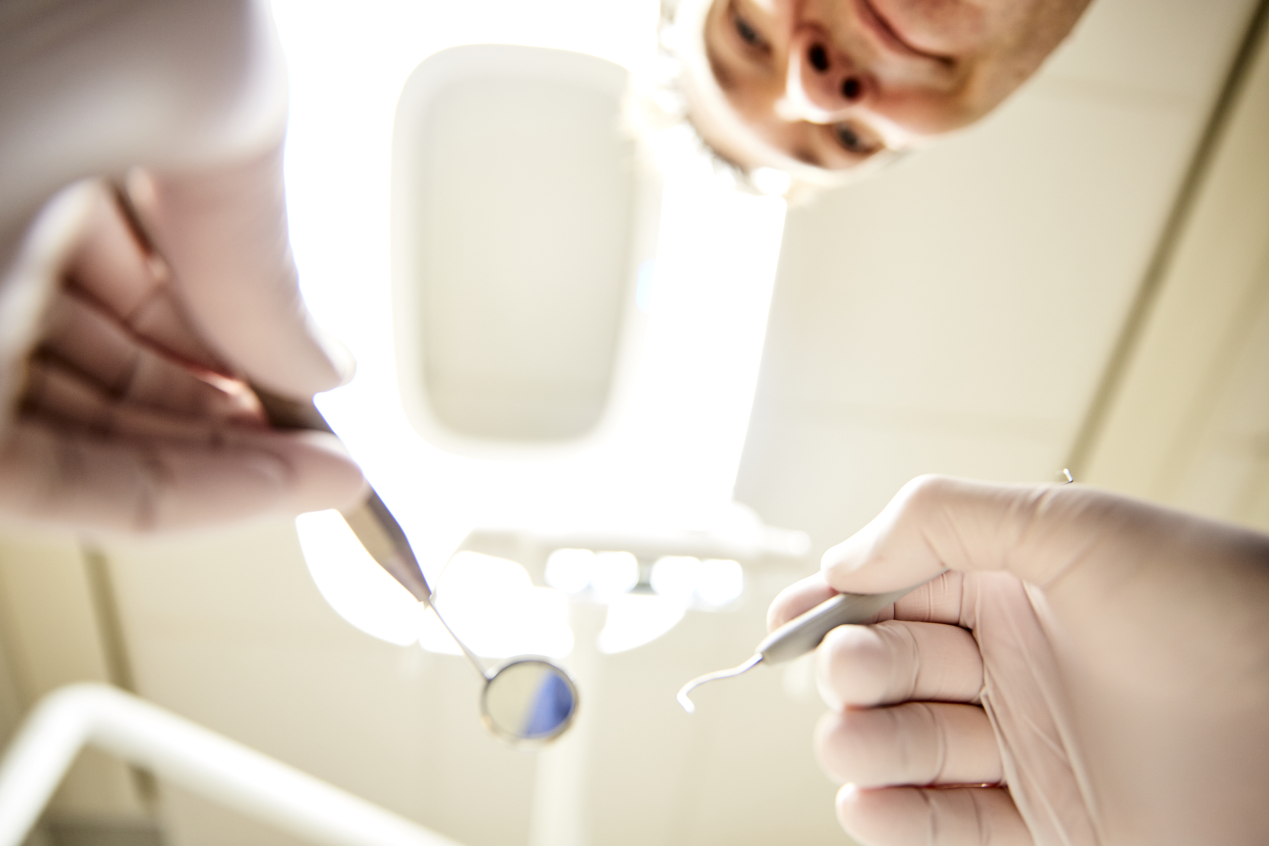 Vy från patientens stol när tandläkare undersöker